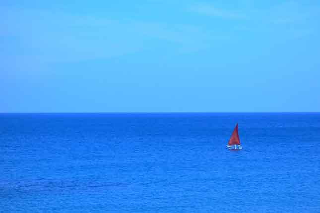 Neals Yard Holidays red sail boat on the sea