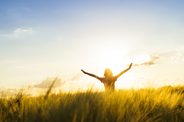 Gratefulness – a happy person in a field with sunny sky © Oksana Shufrych/Shutterstock