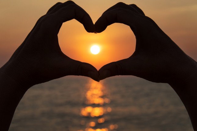 Valentine's Day: Hands make a heart shape against a setting sun © EMprize
