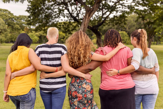Women embracing by tree for International Women's Day