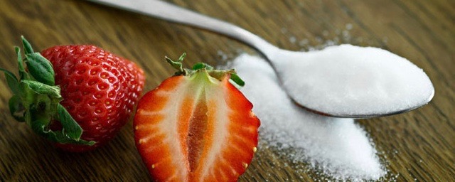 spoon full of white sugar with cut strawberry